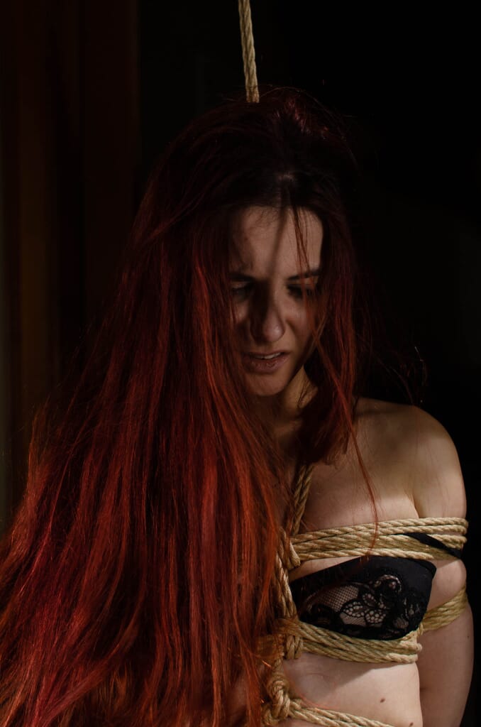 Ritratto di Marta Tenshiko con i capelli rossi sul viso e le corde sopra la lingerie nera