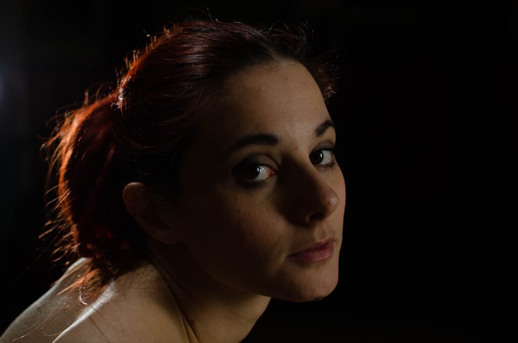Ritratto di Marta Tenshiko illuminata di profilo su uno sfondo scuro