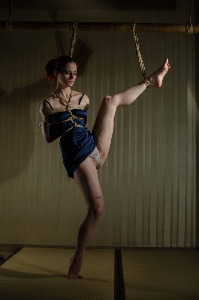 Marta Tenshiko in equilibrio sul tatami con una gamba sostenuta dalle corde