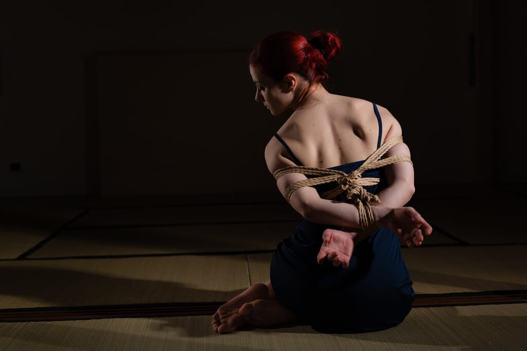 Marta Tenshiko vista di schiena mentre le braccia vengono legate dietro il corpo