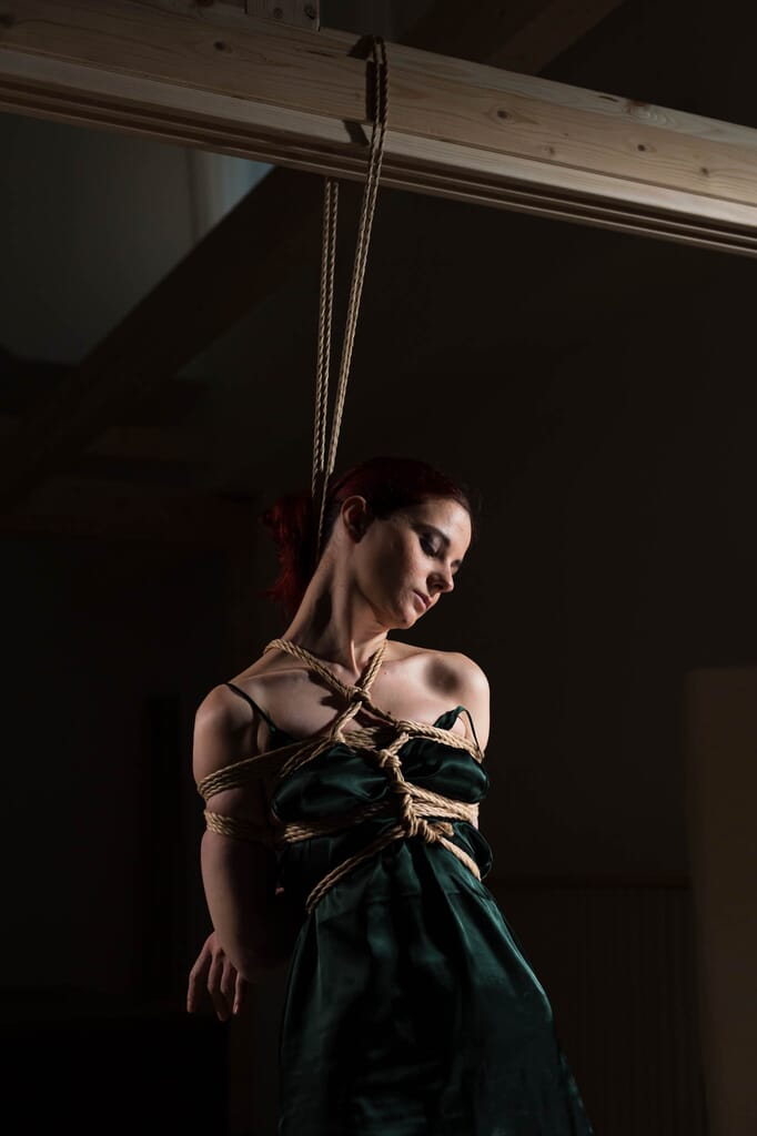 Marta Tenshiko in abito verde con chest piece e cintura di corde, in piedi all'inizio della sequenza